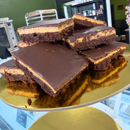 Stack of chocolate brownies with a creamy filling on a gold cake stand.